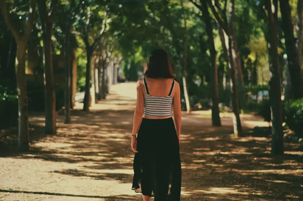 Woman taking a gentle walk along a tree-lined path during hysterectomy recovery