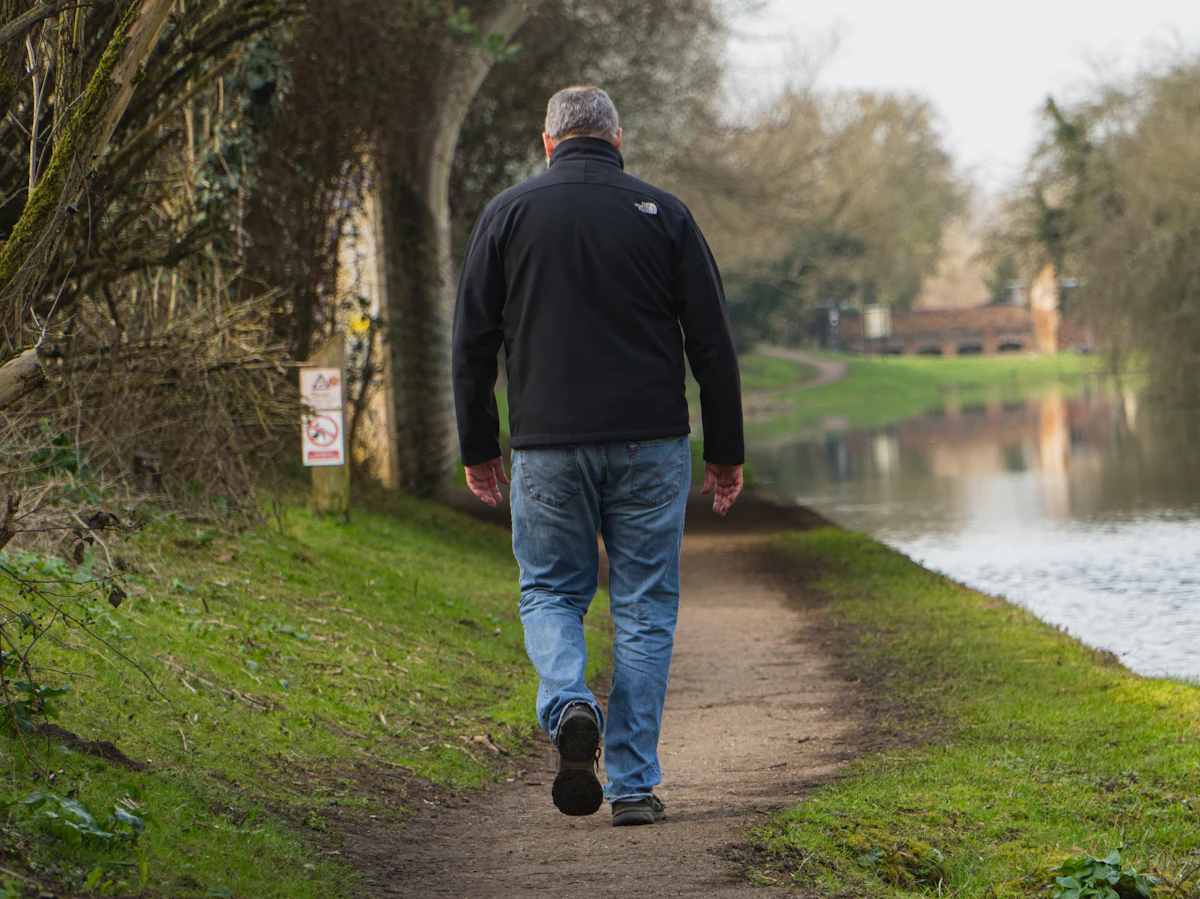Man walking along a riverside path as part of a daily walking routine to reduce an apron belly