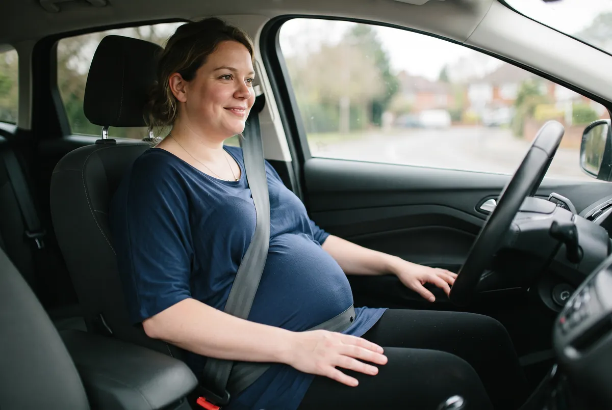 Pregnant woman wearing a seatbelt with the diagonal strap beside her bump and the lap belt low under it